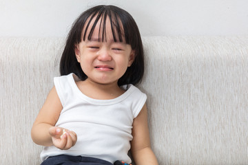Asian Chinese little girl sitting on the sofa crying