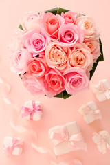 Obraz na płótnie Canvas Bouquet of beautiful pink roses with gifts on pastel pink background