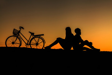 Fototapeta na wymiar Silhouette of sweet couple in love happy time and bicycle in bea