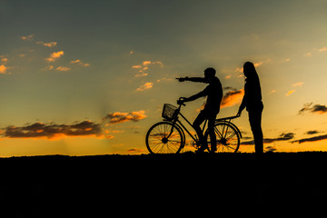 Silhouette of sweet couple in love happy time and bicycle in bea