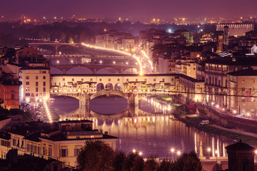 Night view of Florence city with Ponte Vecchio over river Arno and illumination. Travel sightseeing background.
