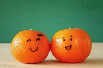 Image of two clementines with drawn smiley faces