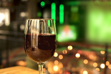 Glass of red wine on blurred lights background