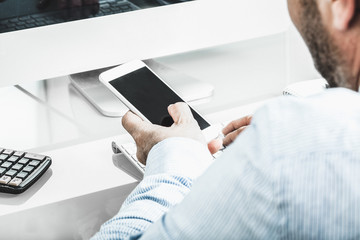 Geschäftsmann im Büro mit Smartphone am Schreibtisch, anonym v