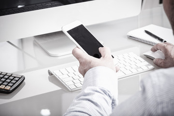 Geschäftsmann im Büro mit Smartphone am Schreibtisch, anonym v