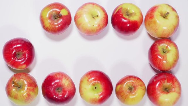 Ripe apples are arranged in shape of square on white background, fruits appear and disappear in different order. Stop motion. Close up, 4K Ultra HD.