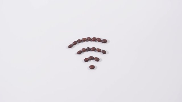 Brown coffee beans set in form of wifi sign on white background, internet connection, arabica, wireless network. Close up, stop motion, 4K Ultra HD.