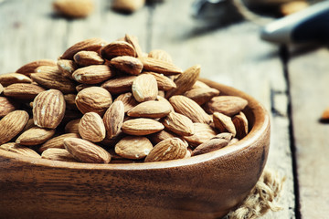 Raw almonds in bowls, old wooden background, selective focus