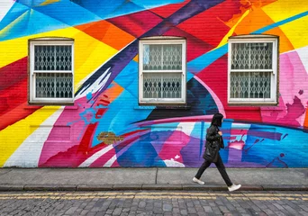Fensterläden in der Wand, die mit Straßenkunst des Regenbogens bedeckt sind © Andrew Deer