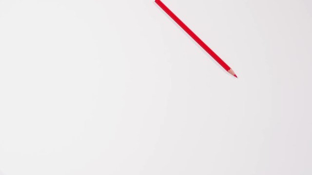 Red pencil swings from side to side as pendulum on white background, imitation of clock part, time. Stop motion. Close up, 4K Ultra HD.