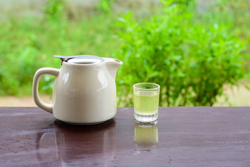 Hot green tea pot and glass on wood table