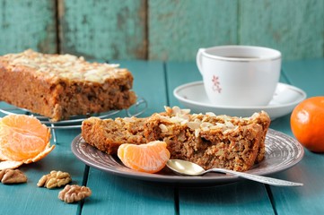 Fototapeta na wymiar Homemade carrot cake with fresh clementines on turquoise backgro