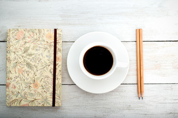pencil, notebook, white cup on the desk stand. Workplace