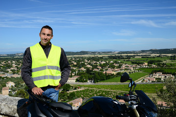 Fototapeta premium handsome young man biker with yellow mandatory safety vest under seat of his motorbike