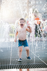 Happy kid playing in a fountain with water