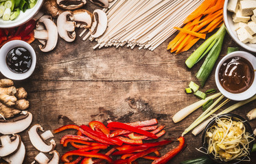 Asian food background with vegetarian cooking ingredients and chopsticks : tofu, noodles, ginger, lemongrass, cut vegetables, Sprout,green onion ,hoisin and austern sauce,  top view, frame