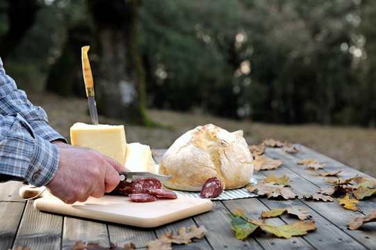 Outdoor eating with bread, cheese and sausage.