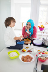 Muslim traditional woman with little son in modern white kitchen