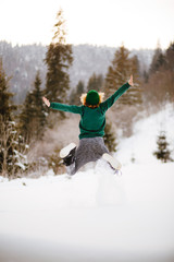 Naklejka na ściany i meble Happy girl jumping in the winter snowy mountains.