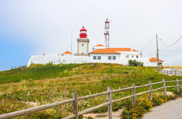 Fototapeta na wymiar Lighthouse at Cape Roca, Sintra, Portugal with tourist people and blurred sky background.