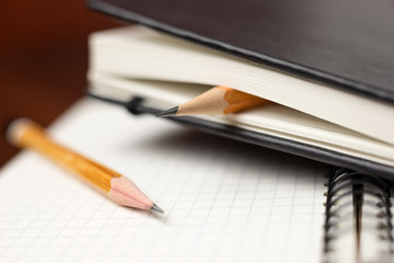 Pencils on the pages of an closed notebook for records