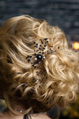 beautiful evening hairstyle on blonde hair with black decoration of stones