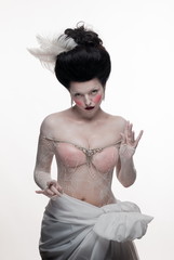 emotional brunette actress woman in a transparent lace dress and lush hair with white feathers on a...