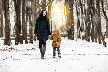 Happy mother and baby in winter park. Family outdoors.