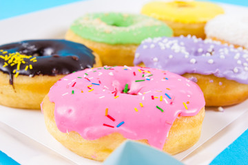 Strawberry, chocklate and other donuts in paper box on blue background