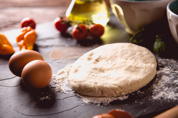 Preparing home pizza on wooden table with ingredients