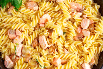 Home made Tasty Pasta with Salmon, mushrooms, lemon, herbs and cheese close up background