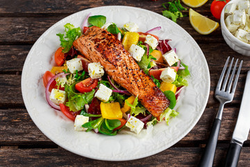 Fried Salmon steak with fresh vegetables salad, feta cheese. concept healthy food.