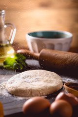 Dough with flour on wooden table, preparing homemade pizza