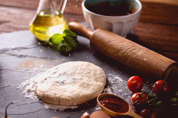 Dough with flour on wooden table, preparing homemade pizza