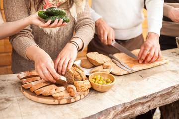 the yong people cuts bread and tomatoes on a wooden board.