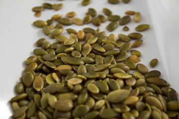 Lightly salted pumpkin seeds on white tray, close up