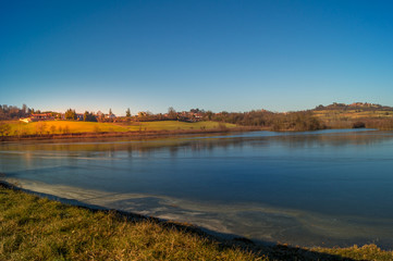 Fototapeta premium obszar zielonej trawy nad jeziorem z błękitnym niebem, okolica i farma wokół jeziora, nasłoneczniona woda