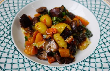 Plate of vegan potato gnocchi with butternut squash, mushrooms and kale