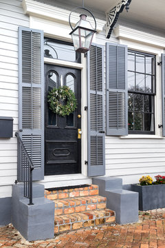 Front door and brick steps of a quaint cottage house with shutters