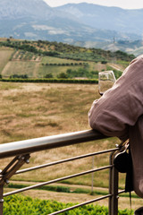Man drinking a glass of red wine looking in to a wonderful landscape in the middle of Italy. Uomo che beve un bicchiere di vino rosso contemplando un meraviglioso paesaggio collinare del centro Italia