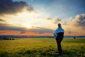 Man wistfully watching the sunset on a hill in the countryside