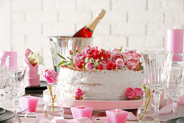 Delicious cake decorated with flowers on brick wall background