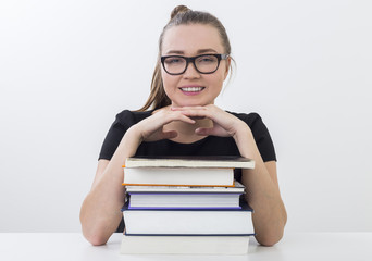 Happy girl in glasses and a stack of books