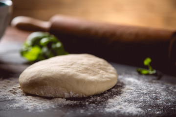 Fototapeta na wymiar Dough with flour on wooden table, preparing homemade pizza