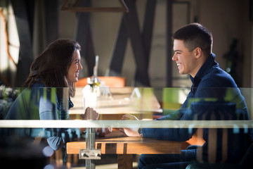 Couple in love in a cafe smiling and looking eachother