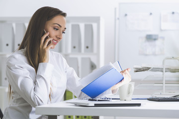 Woman in white blouse with notebook and cell phone