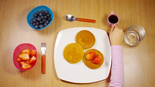 4K Time lapse of child decorating and eating warm pancakes at the breakfast table