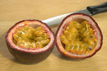 Cut open Passion Fruit or Maracuya, with knife, brightly lit on wooden background