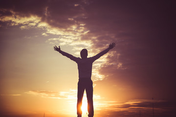 happy man with hands up on sunset background..