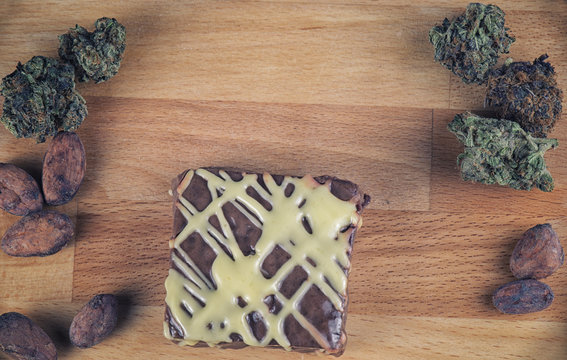 Pot brownie detail over wood with cannabis buds